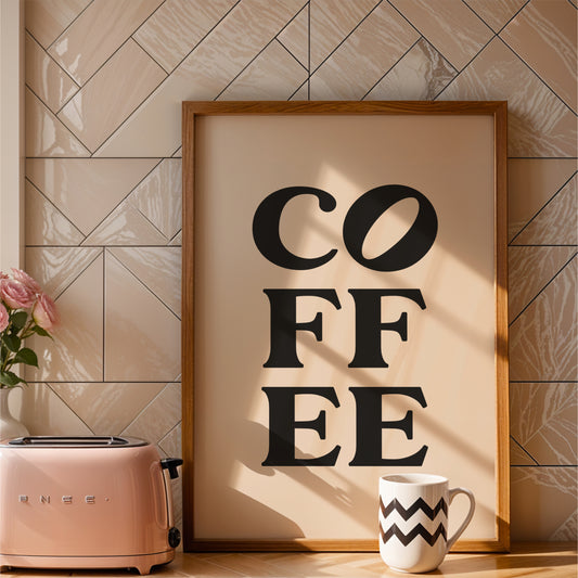 a framed poster with the word "COFFEE" in bold black letters, placed on a kitchen counter next to a pink toaster and a white coffee mug.