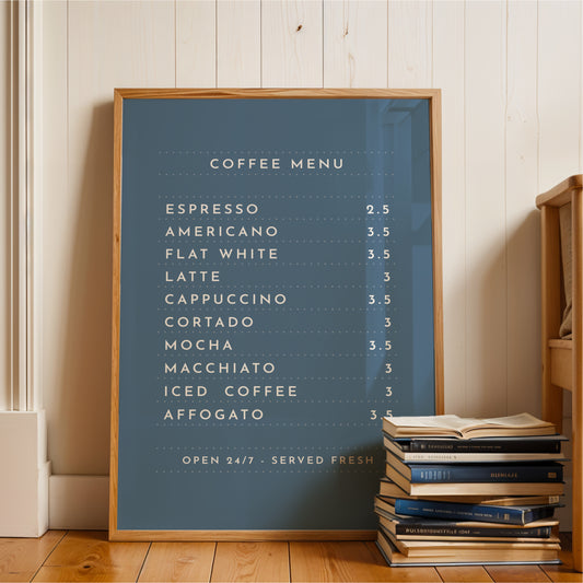 A blue framed coffee menu board displaying a list of coffee drinks, placed next to a stack of books on a wooden floor.