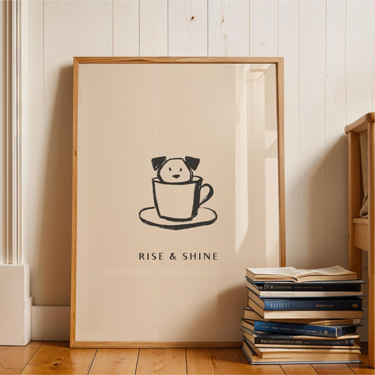 A framed poster with a cartoon dog sitting in a cup, accompanied by the text "RISE & SHINE" on the poster.