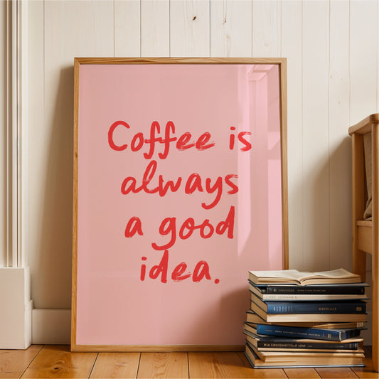 A framed poster with the text "Coffee is always a good idea" is displayed on a wooden floor next to a stack of books.