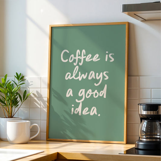 A framed poster with the text "Coffee is always a good idea" is displayed on a kitchen counter, accompanied by a coffee maker and a potted plant.