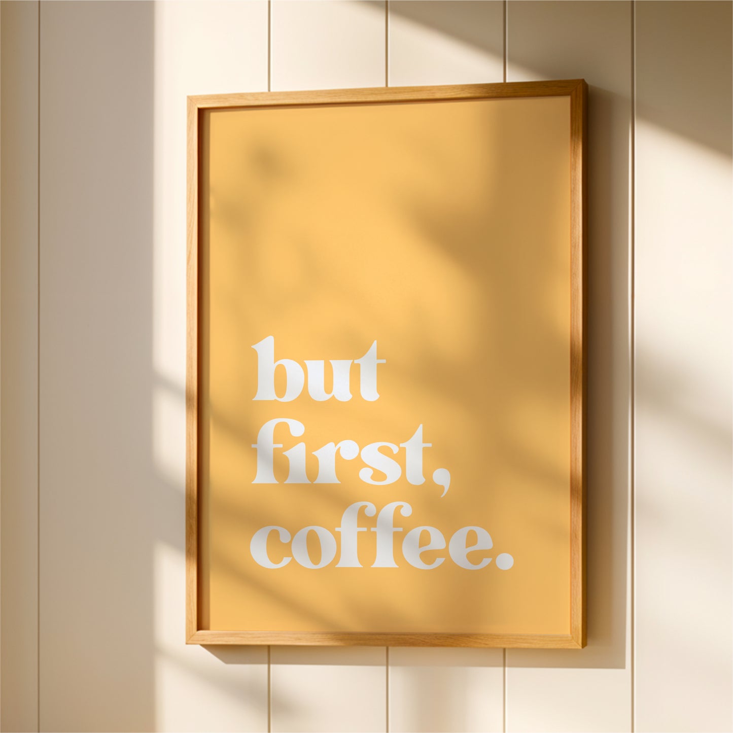 A framed poster with the text "but first, coffee" displayed on it.