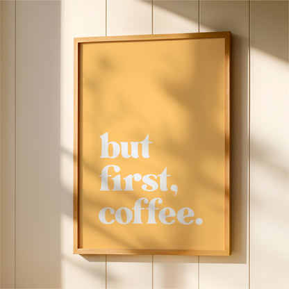 A framed poster with the text "but first, coffee" displayed on it.