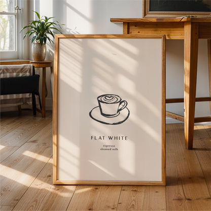 A framed poster with a simple black and white illustration of a cup of espresso on a saucer, along with the text "FLAT WHITE" and "eppresso steamed milk" printed on it.