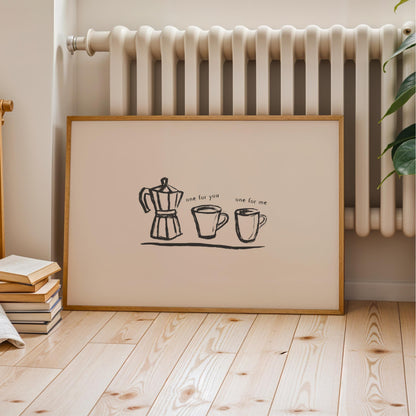 A framed print with a simple black and white illustration of a coffee maker, two mugs, and text that reads "one for me" is displayed on a wooden floor next to a radiator.