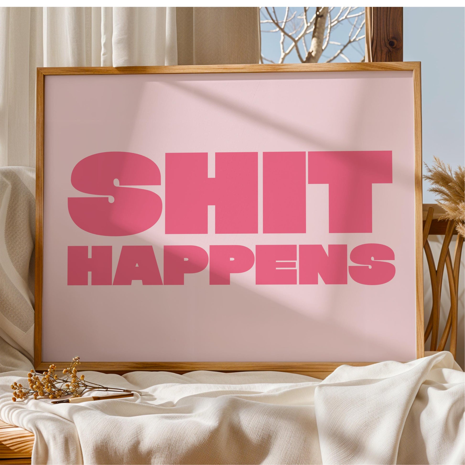 A framed poster with the text "SHIT HAPPENS" in large pink letters.