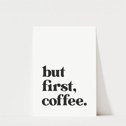 A white poster with the text "but first, coffee." printed on it.