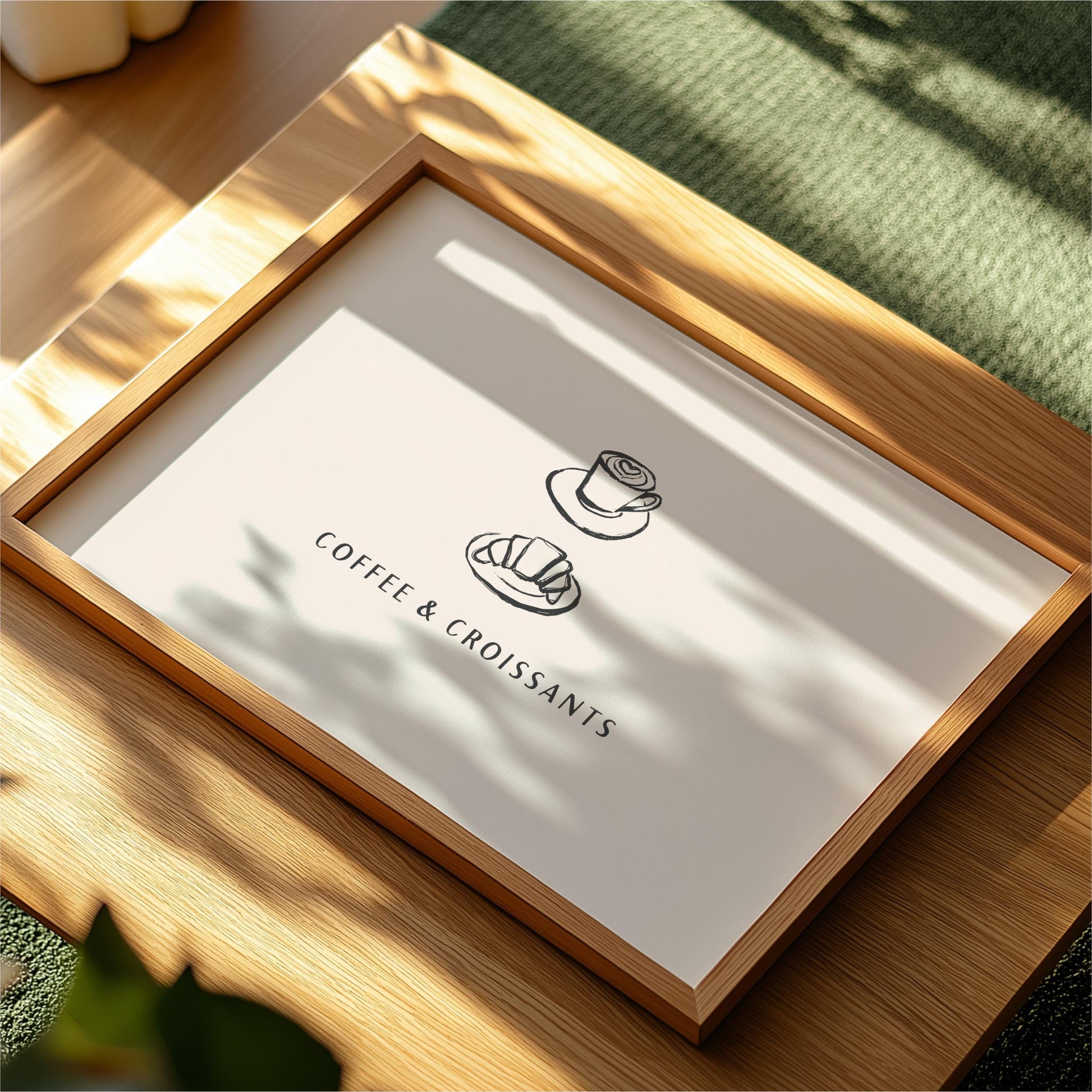 A framed poster or sign with the text "COFFEE & CROISANTS" and two simple illustrations of a coffee cup and a croissant.