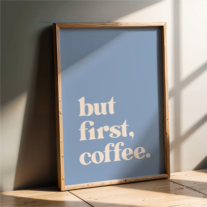 A framed poster with the text "but first, coffee" on it, leaning against a wall.