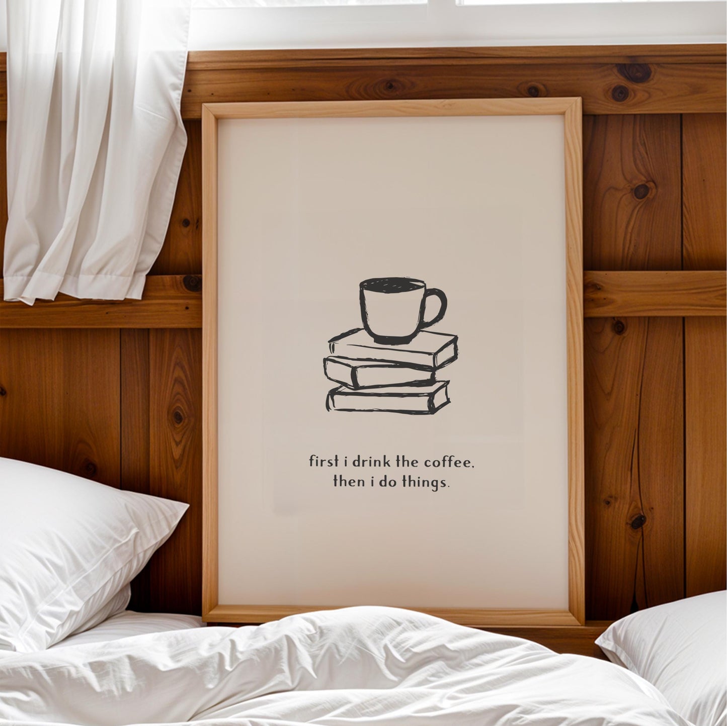 A framed poster with a simple black and white illustration of a coffee cup on a stack of books, accompanied by the text "first I drink the coffee. Then I do things."