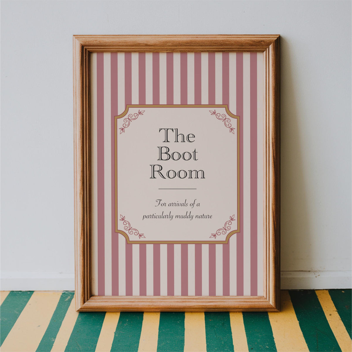 a framed sign with a pink and white striped background and decorative elements, indicating that it is a sign for "The Boot Room".