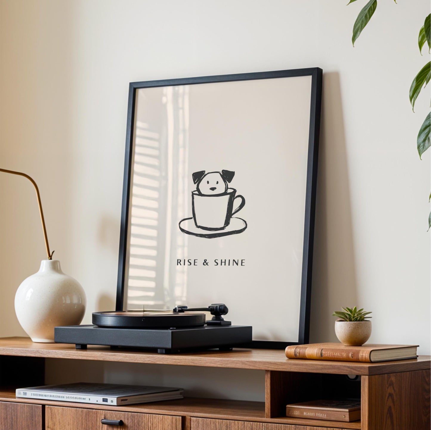 a framed poster with a cartoon dog inside a cup, placed on a wooden shelf next to a record player and some books.