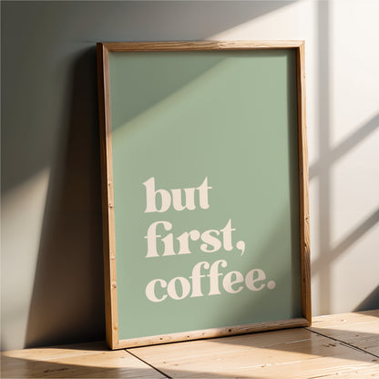 A framed poster with the text "but first, coffee" on it, leaning against a wall.