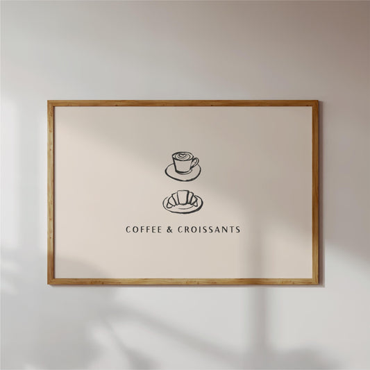 a framed poster with a simple illustration of a coffee cup and croissant, accompanied by the text "COFFEE & CROISSAINS" in a black font.