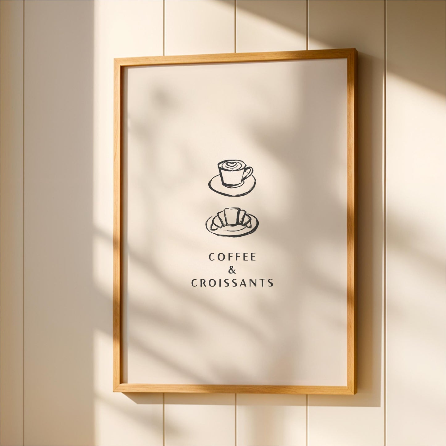 A framed poster with the text "COFFEE & CROISSANTS" and two illustrations of a coffee cup and croissant on a plate.