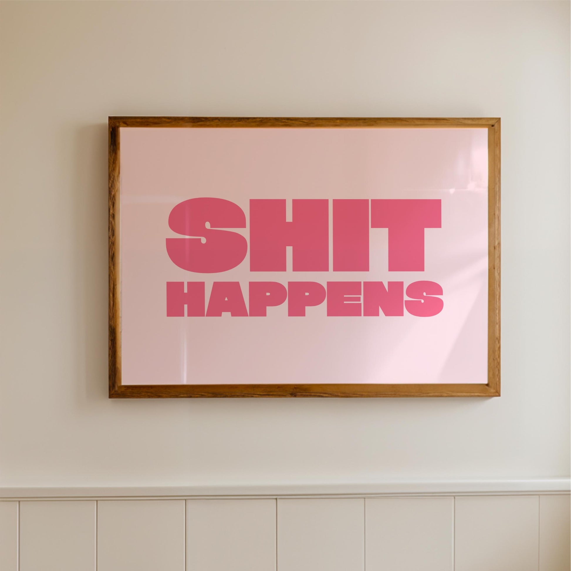 a framed poster with the text "SHIT HAPPENS" in bold pink letters.