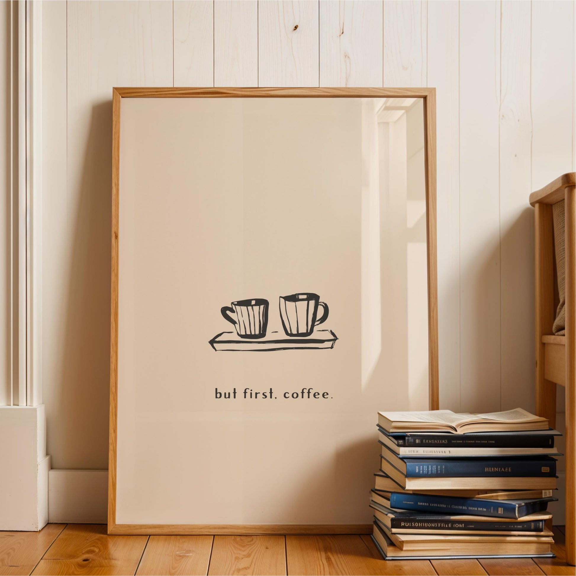 A framed poster with the text "but first. coffee" is displayed on a wall next to a stack of books.