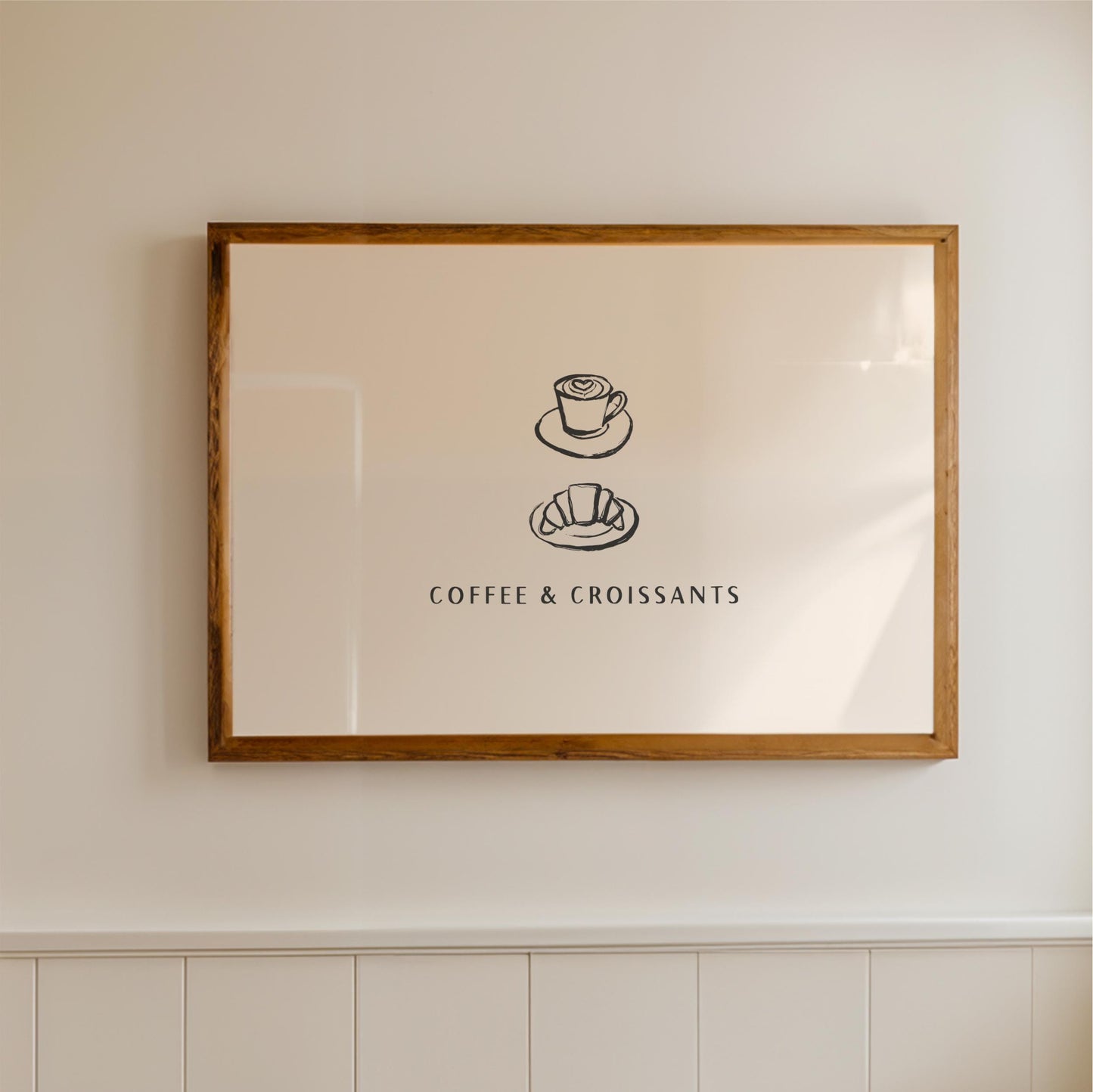 A framed picture hanging on a wall, depicting a cup of coffee and a croissant, with the text "COFFEE & CROISSAINS" below the illustrations.