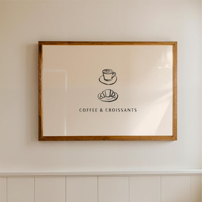 A framed picture hanging on a wall, depicting a cup of coffee and a croissant, with the text "COFFEE & CROISSAINS" below the illustrations.