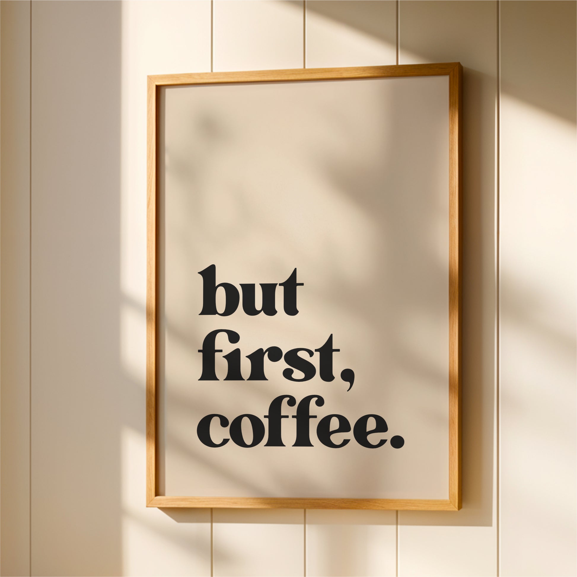 A framed poster with the text "but first, coffee."