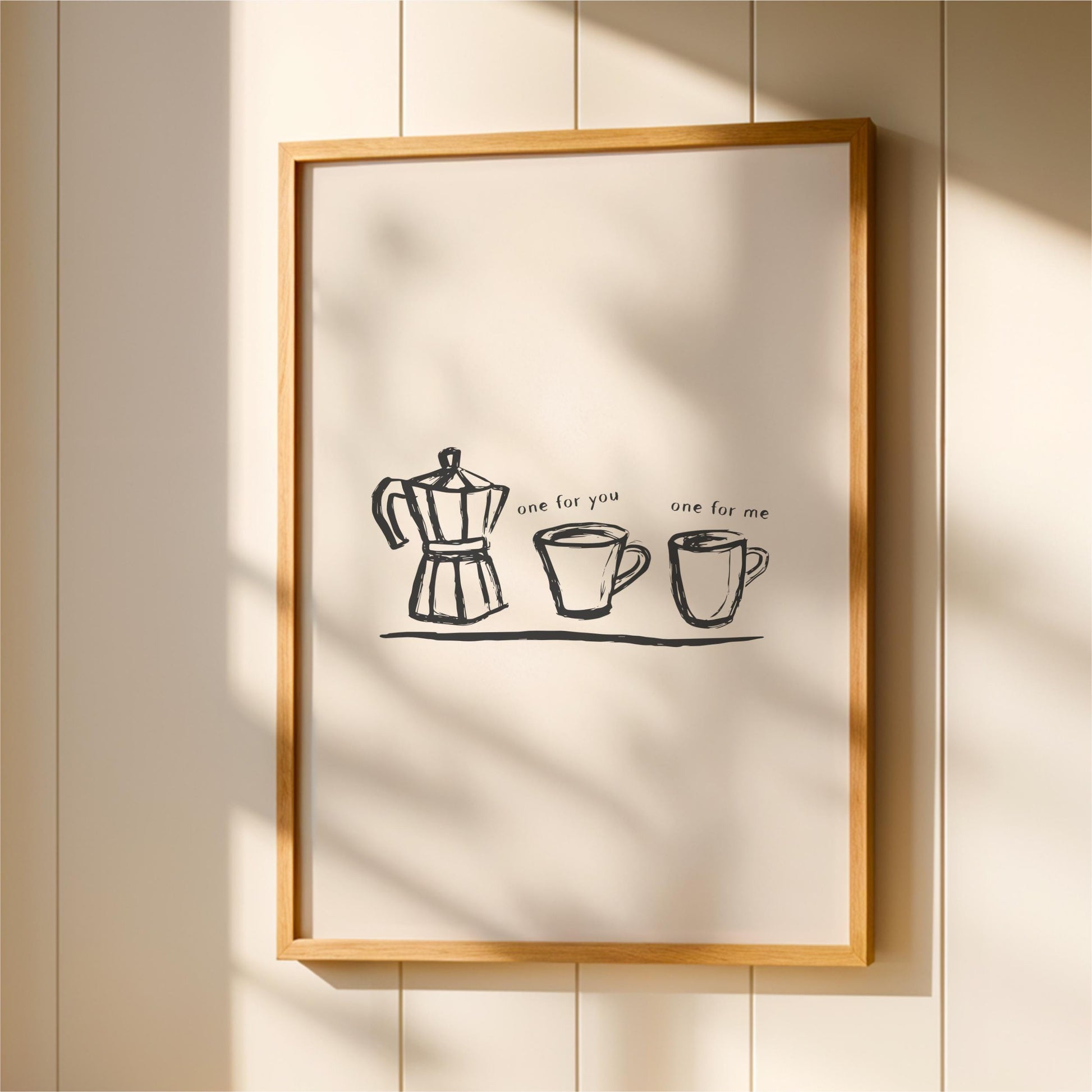a framed artwork with a simple black and white illustration of a coffee maker and two cups, accompanied by the text "one for you one for me".