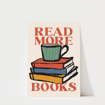a stack of colorful books with a mug on top, accompanied by the text "READ MORE BOOKS" in a bold, red font.