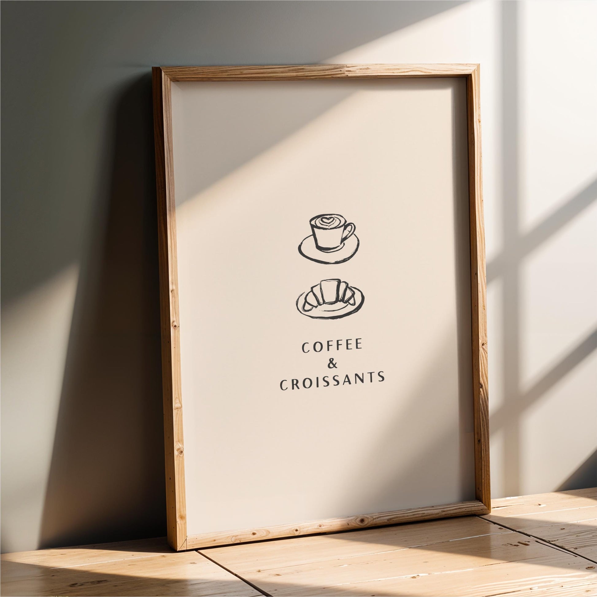 A framed poster with the text "COFFEE & CROISSANTS" and two illustrations of a coffee cup and a croissant.