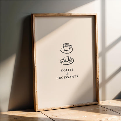 A framed poster with the text "COFFEE & CROISSANTS" and two illustrations of a coffee cup and a croissant.