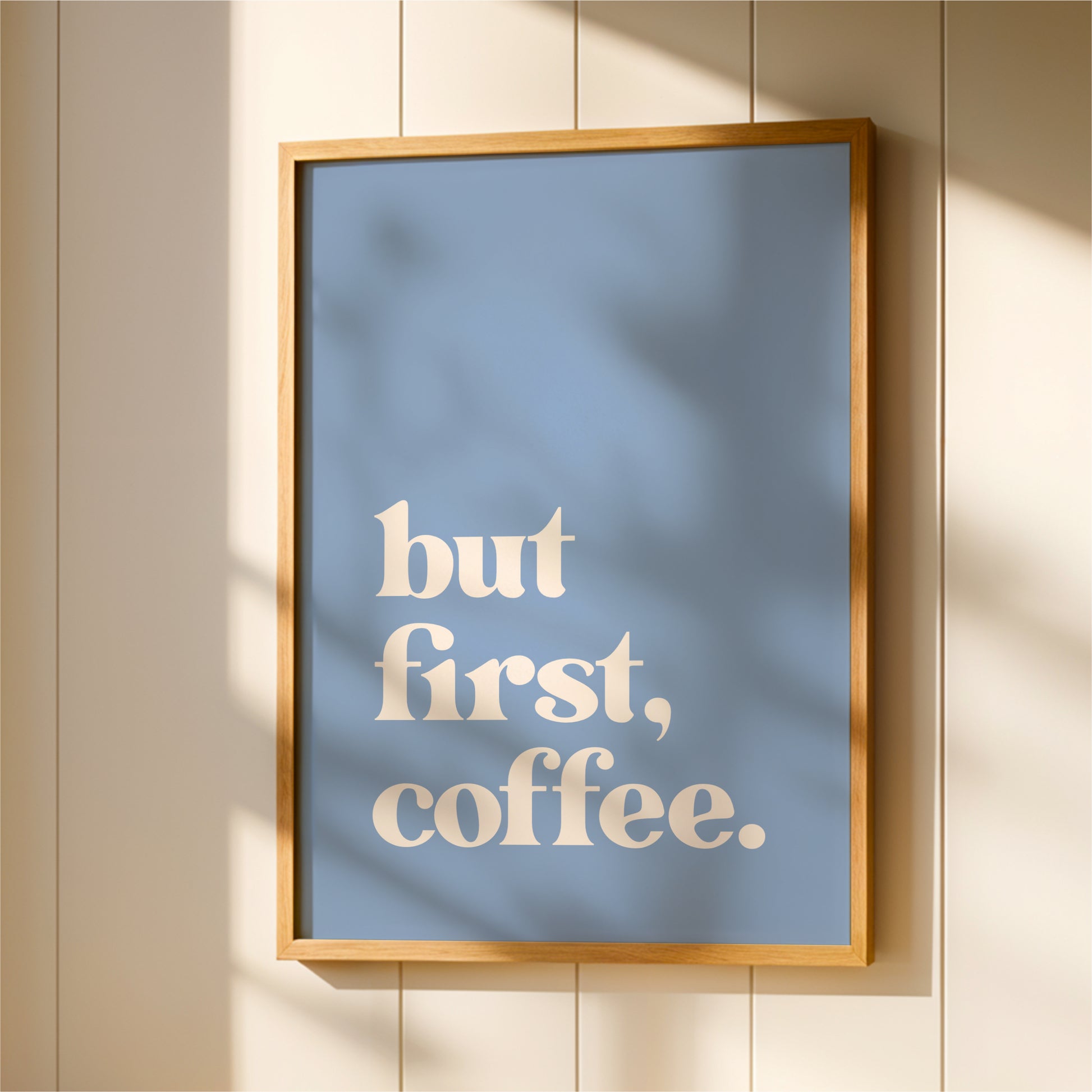 A framed poster with the text "but first, coffee."