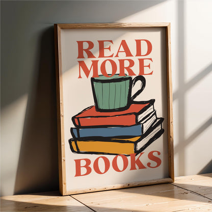 A framed poster with the text "READ MORE BOOKS" and an illustration of a stack of colorful books with a green mug on top.