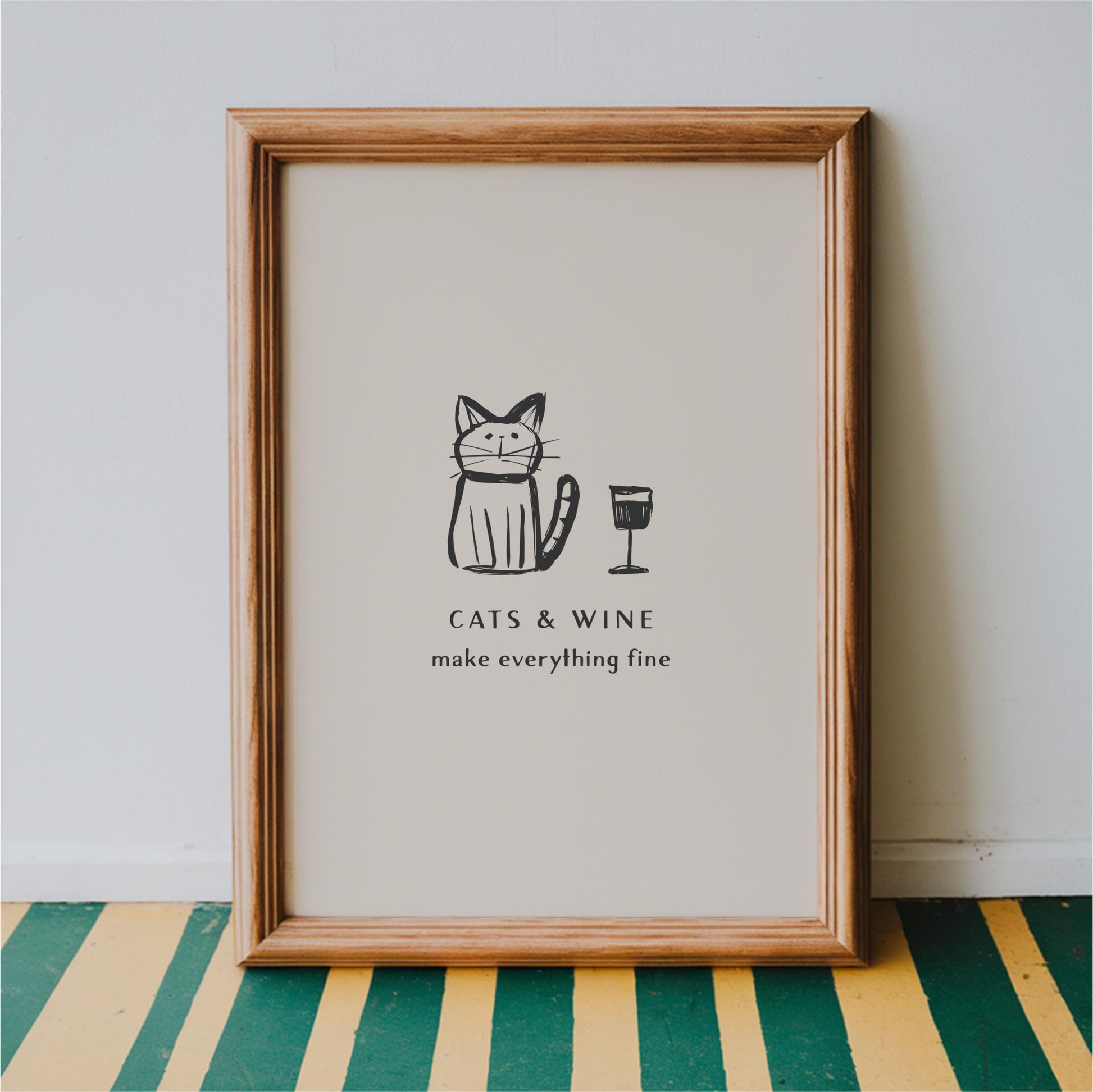 A framed poster with a cartoon cat and a wine glass, accompanied by the text "CATS & WINE make everything fine".