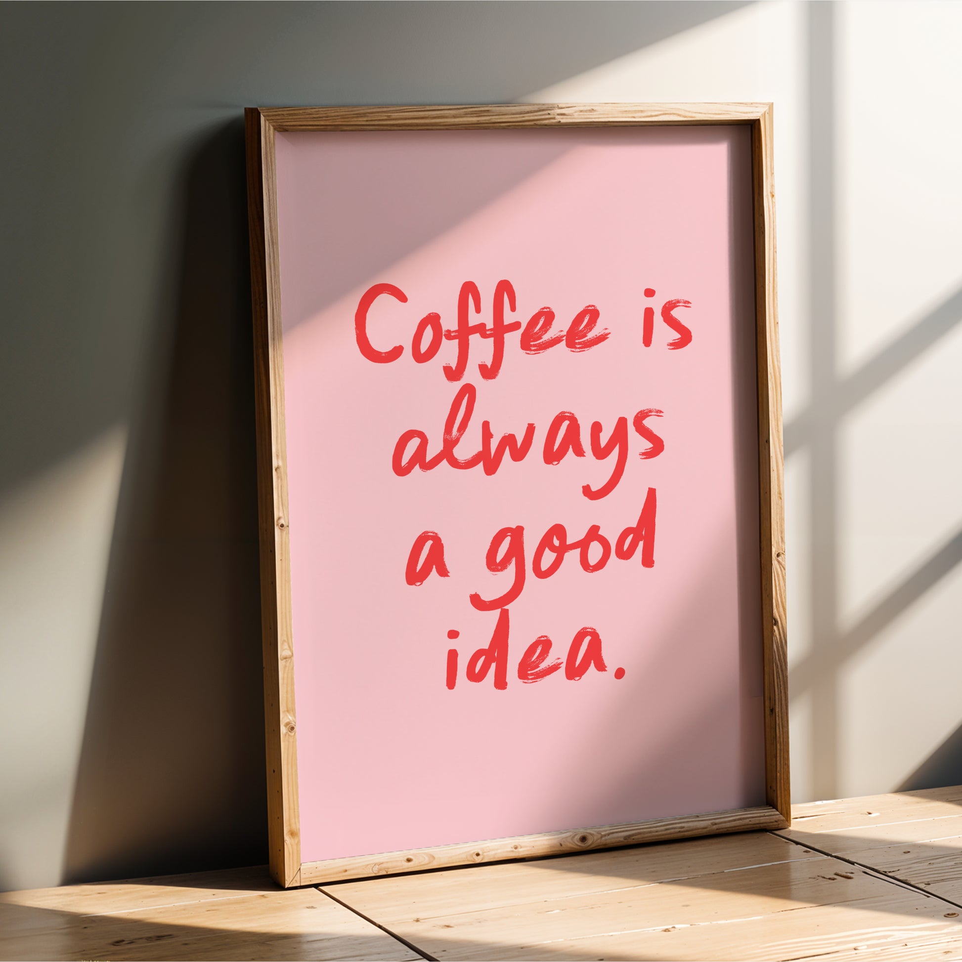 A framed poster with the text "Coffee is always a good idea" in red lettering is leaning against a wall.