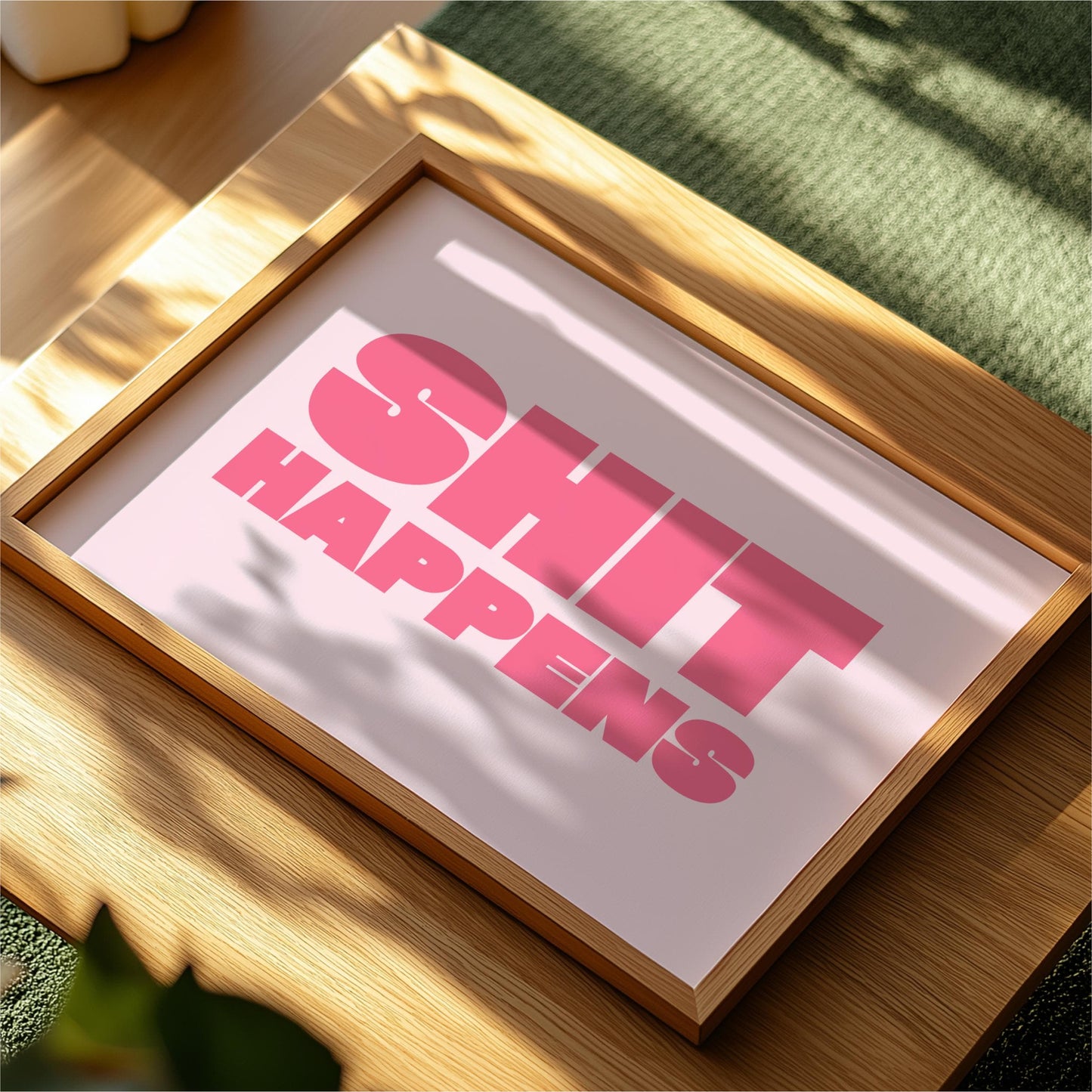 a framed poster with the text "SHIT HAPPENS" in bold pink letters.