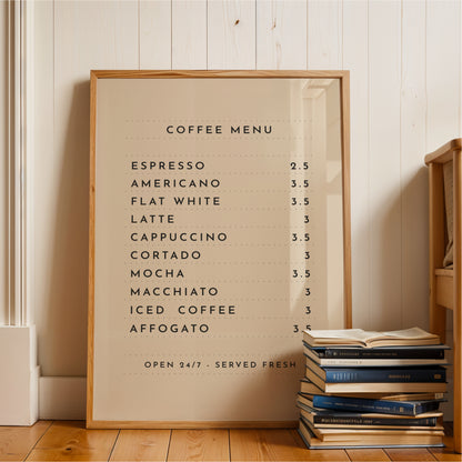 A framed coffee menu is displayed on a wooden floor next to a stack of books.
