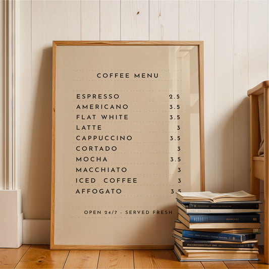 A framed coffee menu is displayed on a wooden floor next to a stack of books.