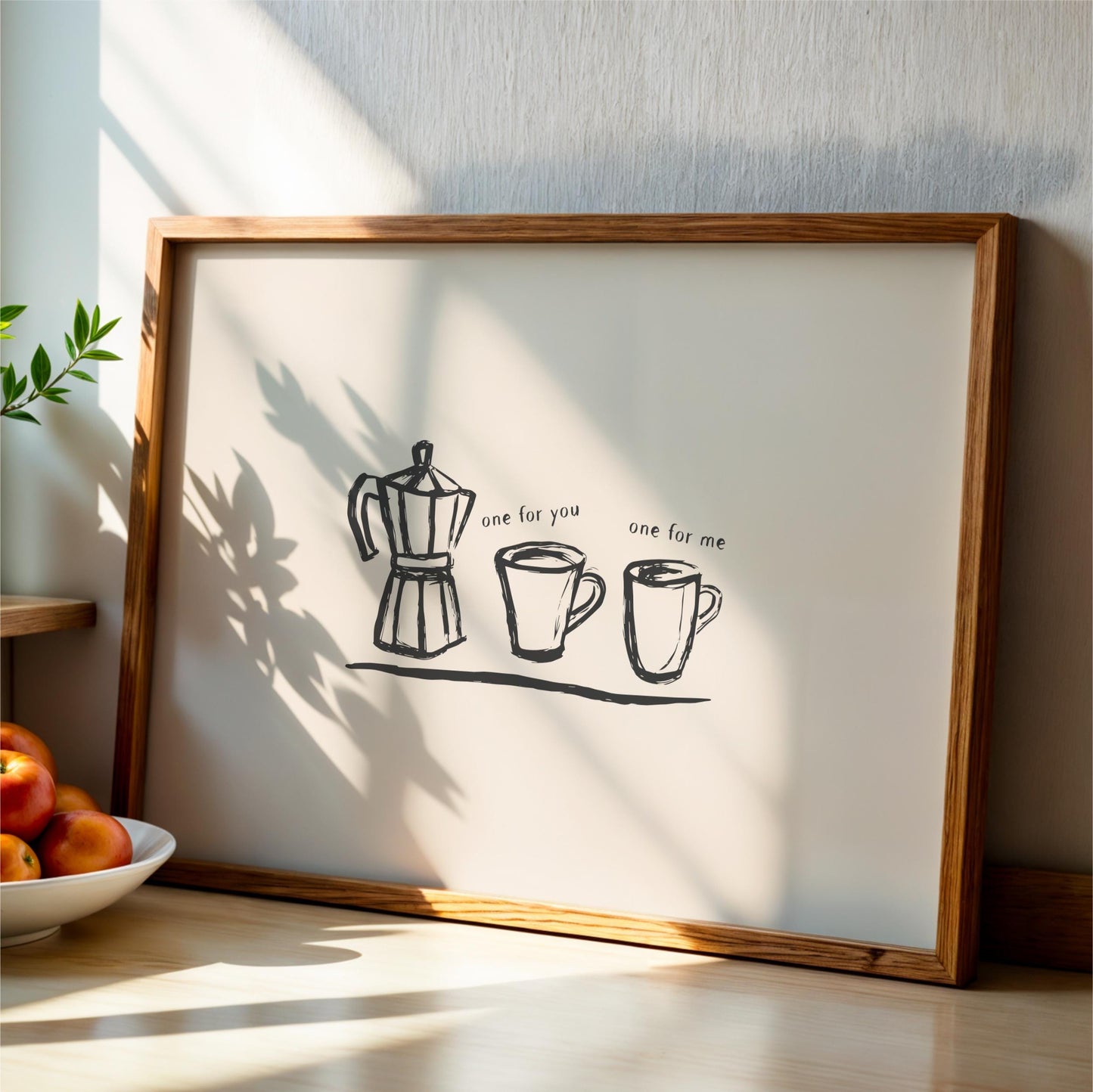 A framed print with a simple black and white illustration of a coffee maker and two cups, accompanied by the text "one for you one for me".