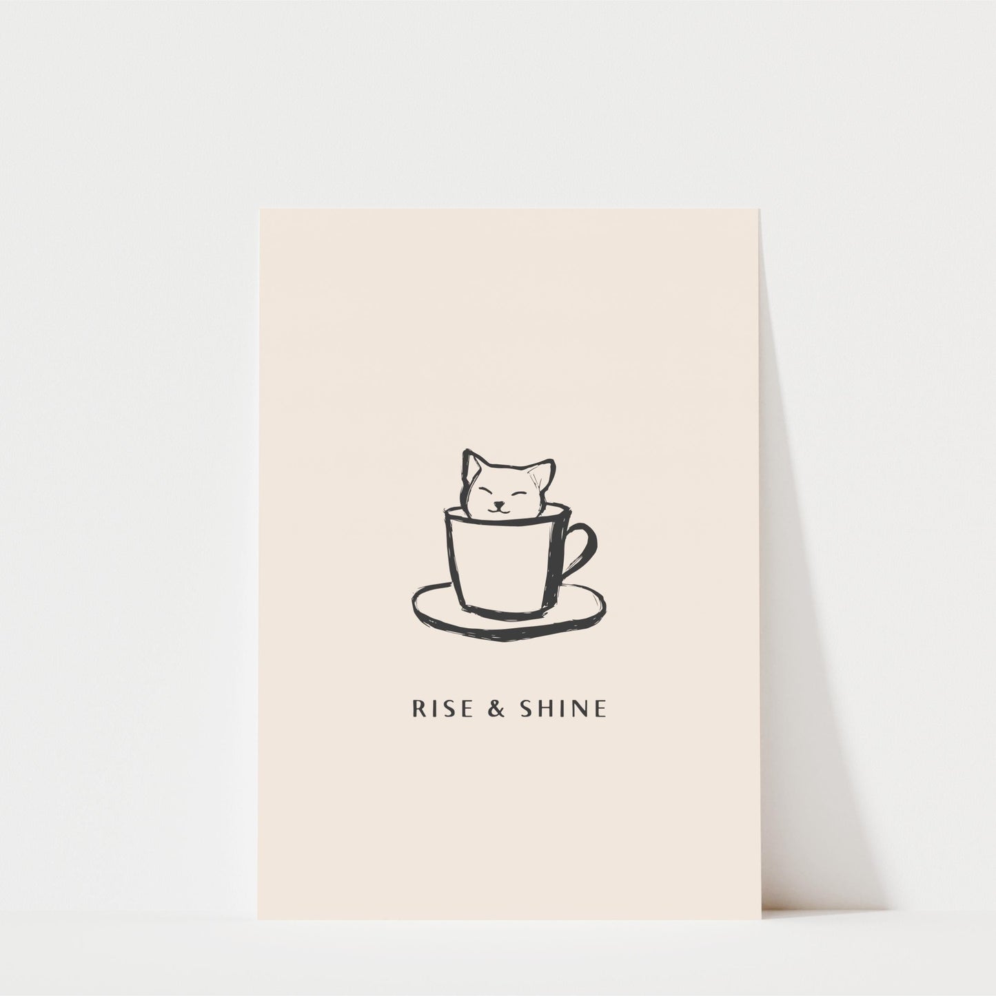 A simple black and white illustration of a cat sitting inside a coffee cup, accompanied by the text "RISE & SHINE" below the image.
